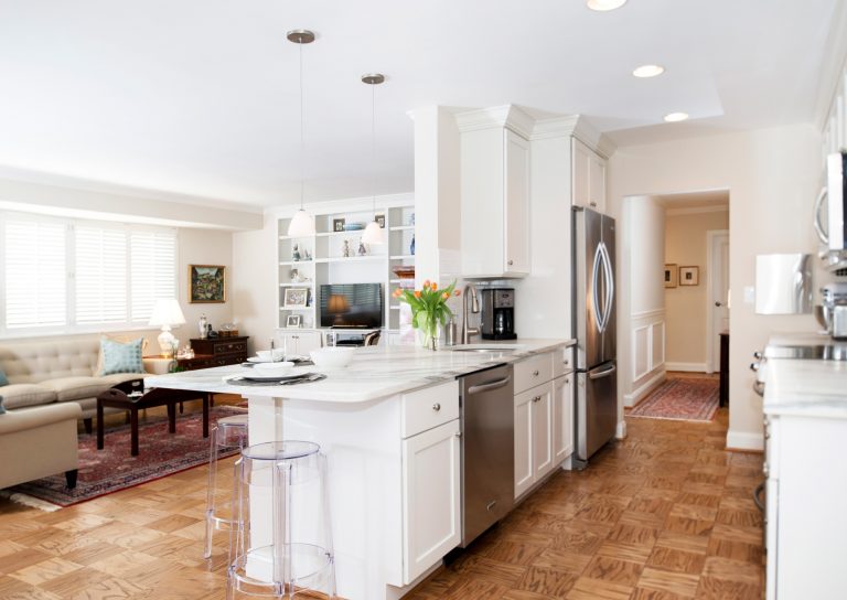 traditional kitchen open to living area divided by peninsula white cabinetry stainless steel appliances pendant lighting parquet floors