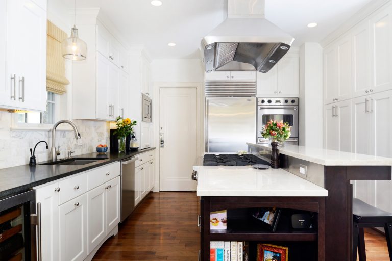 renovated farmhouse kitchen contrasting wood tones white cabinetry with dark ilsand and natural floors stainless steel appliances gas range in island with hood