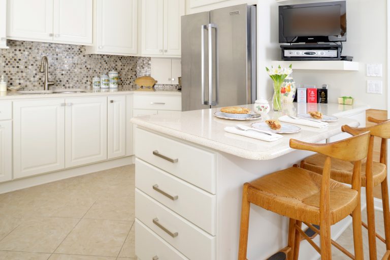 bright white kitchen with peninsula seating mosaic tile backsplash stainless steel appliances gold cabinetry hardware