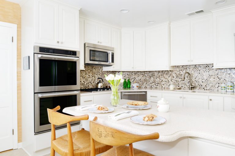 bright white kitchen with peninsula seating mosaic tile backsplash stainless steel appliances