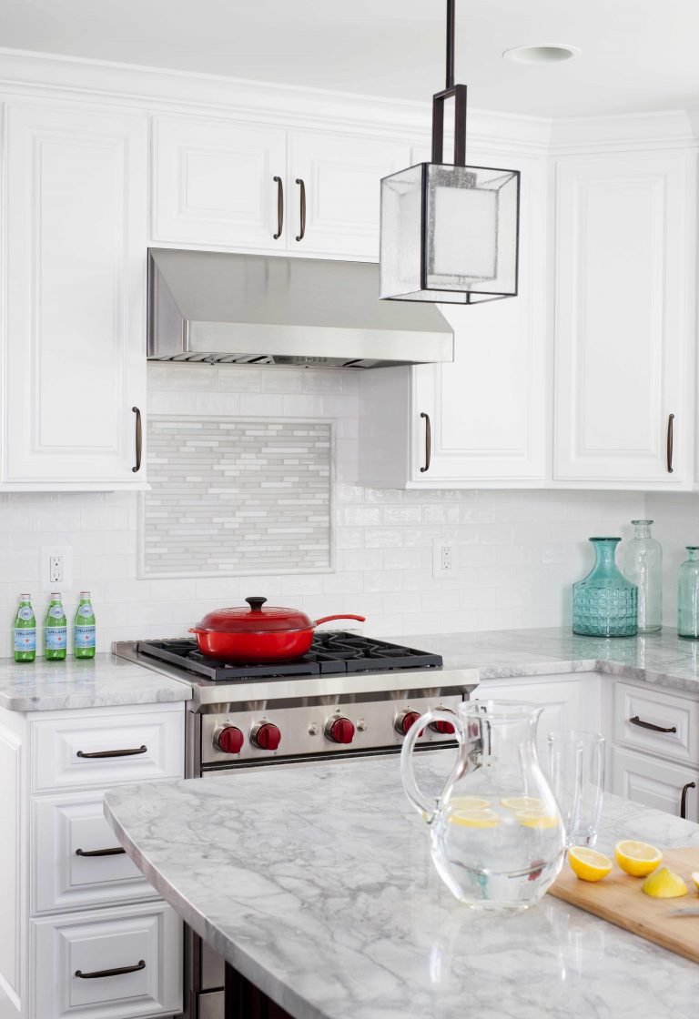 bright white kitchen stainless steel gas range and hood tile detail backsplash