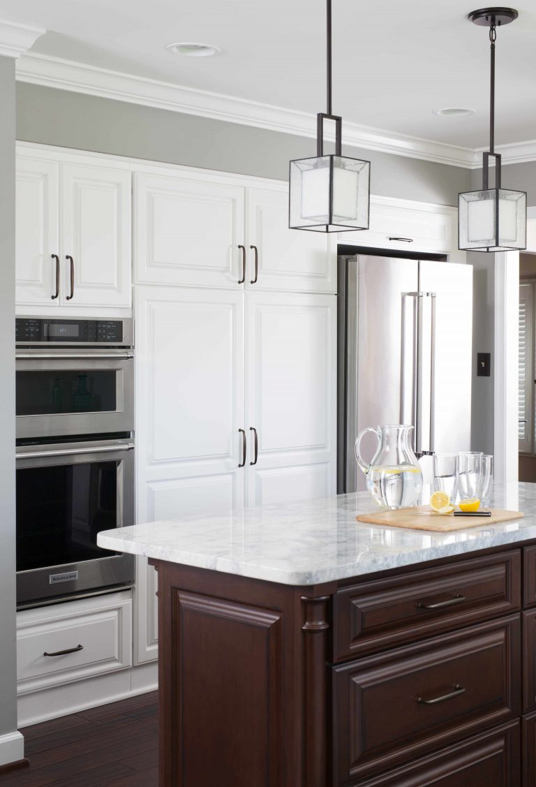 renovated kitchen white outer cabinetry dark wood island and floors pendant lighting stainless steel wall oven