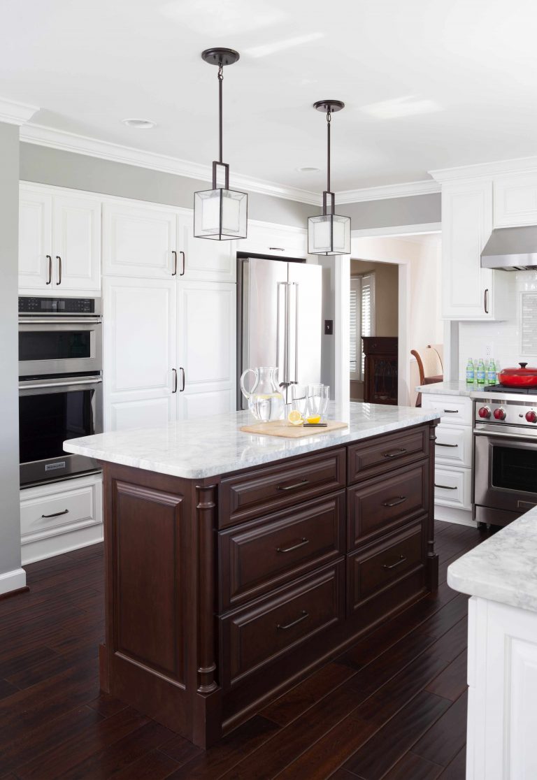 renovated kitchen white outer cabinetry dark wood island and floors pendant lighting stainless steel wall oven