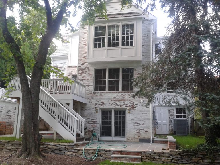 addition on traditional brick virginia home second story deck with stairs to yard ground level sliding doors onto patio