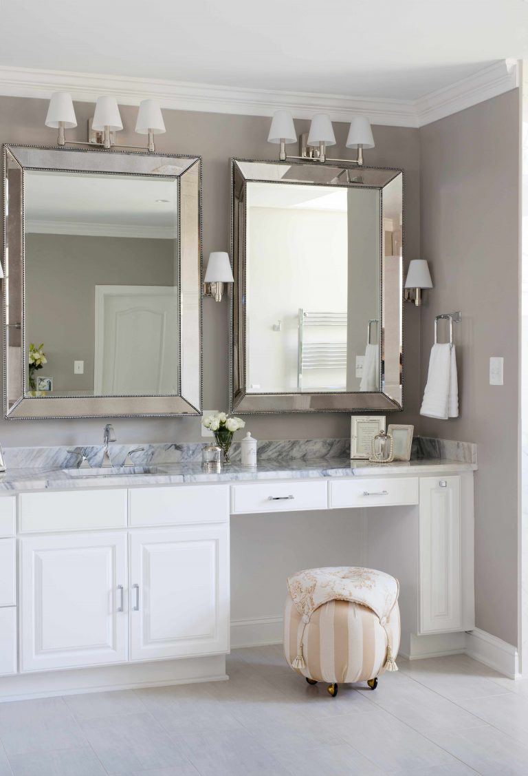 renovated bathroom neutral beige walls white cabinet vanity with built in makeup area sconce lighting crown molding