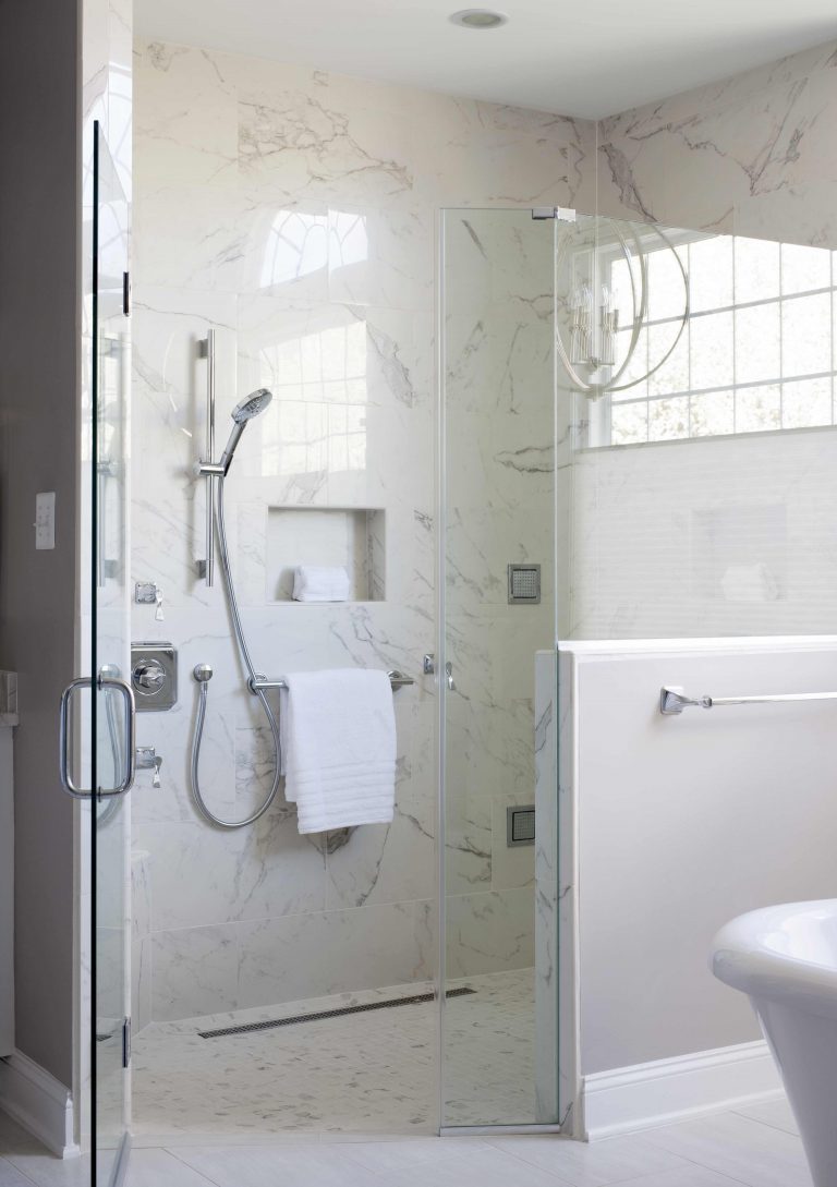 large separate shower stall with half glass wall built in storage nook neutral color palette