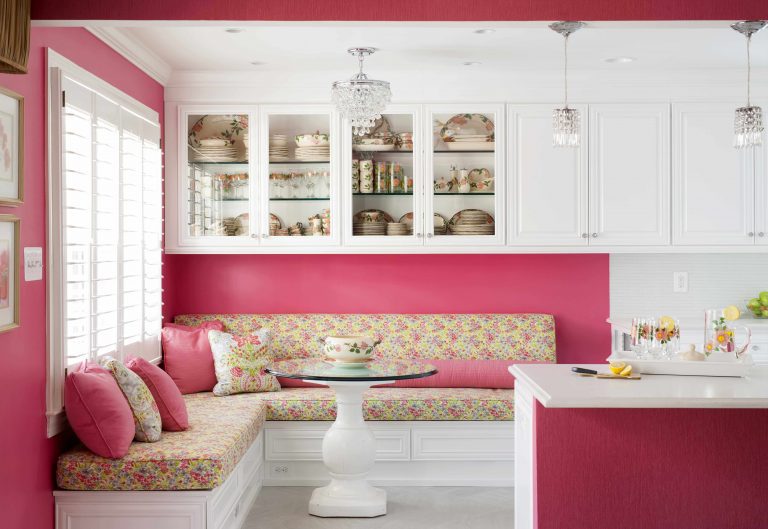 eat in area of kitchen hot pink walls banquette seating upper cabinetry with glass doors