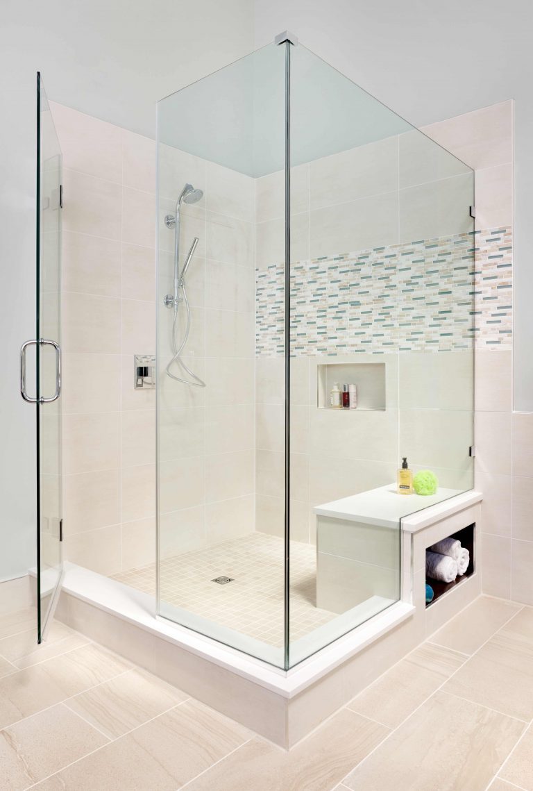 large glass shower stall with built-in bench and storage nooks light neutral color palette