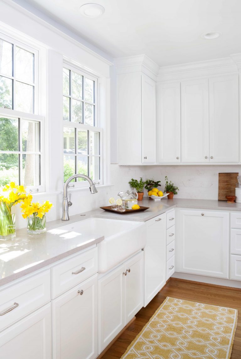 bright kitchen white cabinetry large window farmhouse sink light stained wood floors