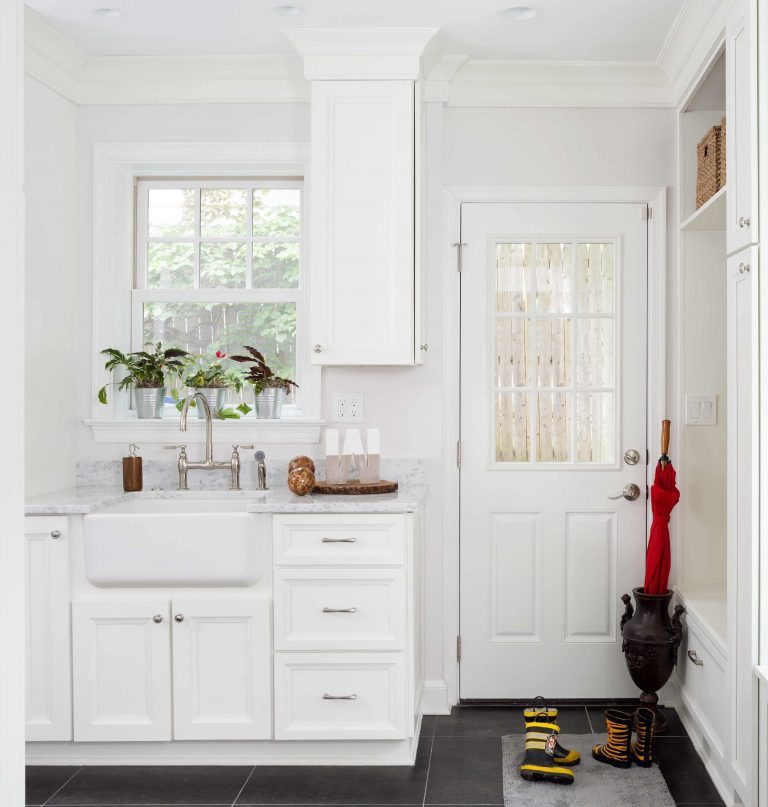 bright white mudroom in Maryland house with built-in cubbies and storage dark wood floors and farmhouse sink nickel hardware