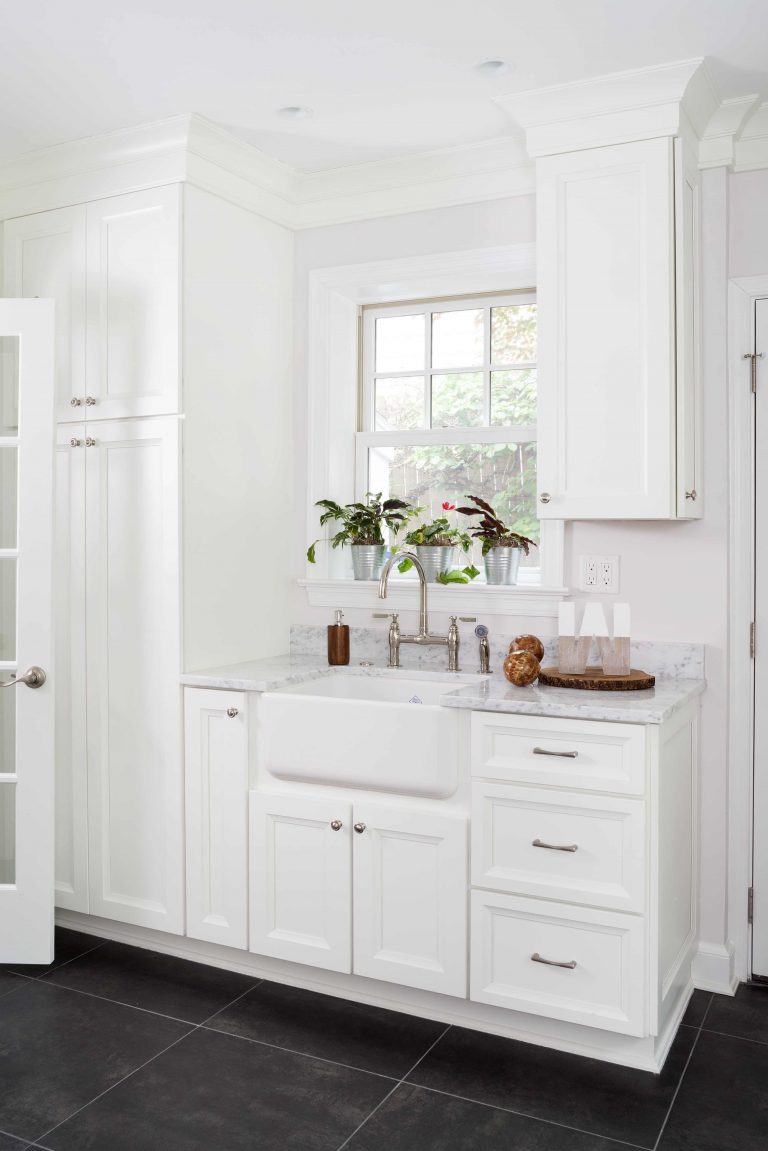 bright white mudroom in Maryland house with built-in storage dark wood floors and farmhouse sink nickel hardware