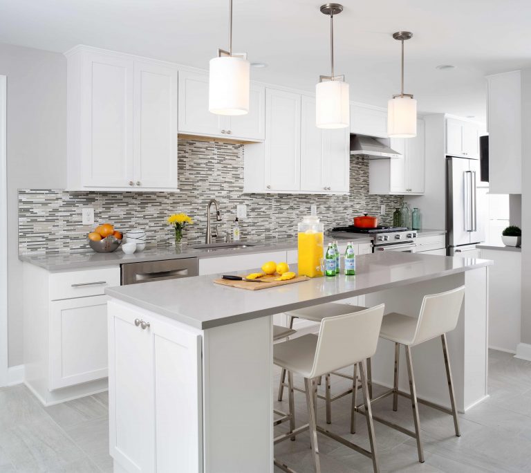 modern kitchen neutral and gray color palette white cabinetry mosaic tile backsplash island with seating pendant lighting