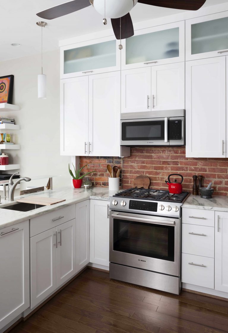 DC kitchen dark hardwood floors white cabinets frosted glass upper cabinets red brick backsplash open to living room