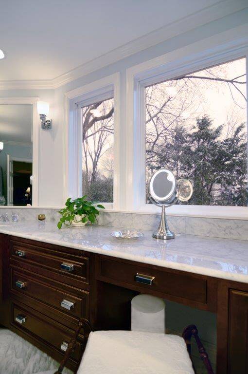 built in vanity in master bathroom facing window natural light dark wood cabinetry