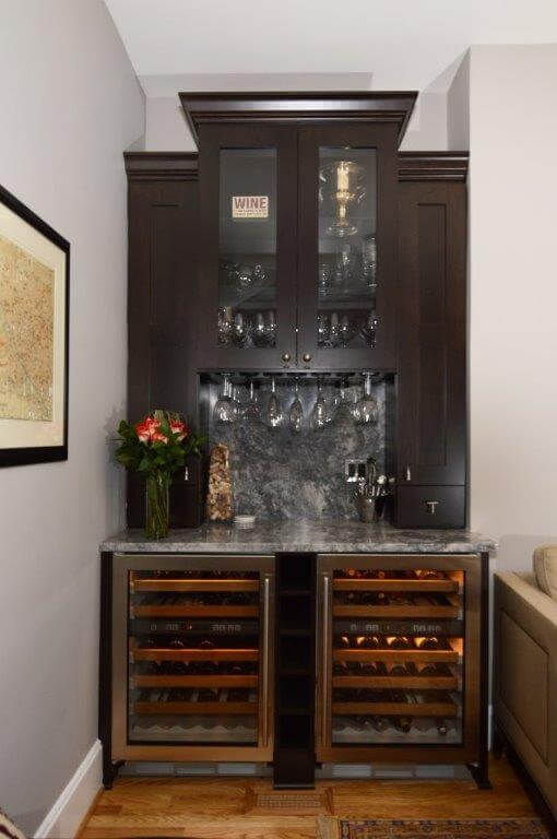 built in bar area with dual beverage refrigerators dark wood cabinetry with glass doors statement backsplash