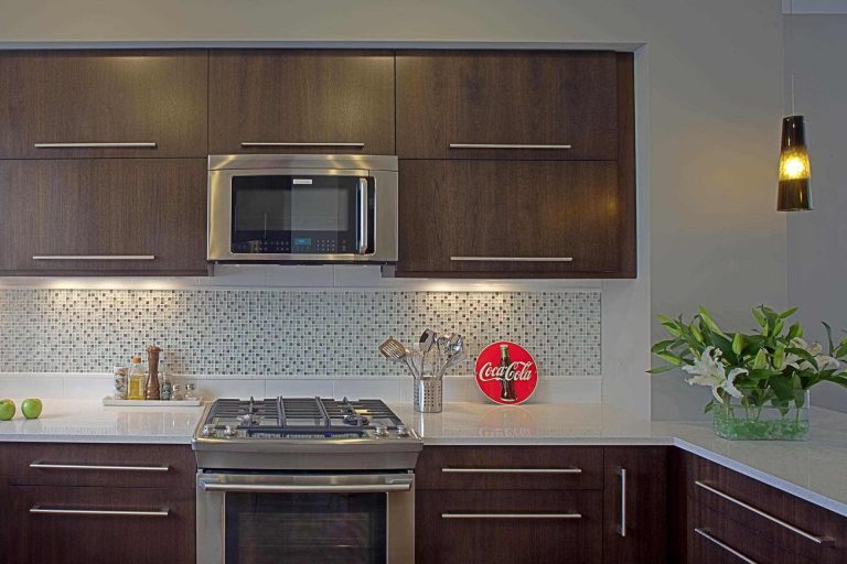 modern kitchen dark cabinetry stainless steel appliances gas range mosaic tile backsplash detail