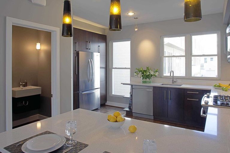 renovated kitchen modern design dark cabinetry white countertops peninsula pendant lighting