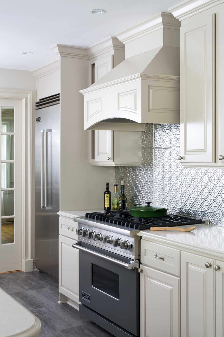 traditional kitchen remodel cream cabinetry gray floors stainless steel gas range with hood stainless steel backsplash crown molding