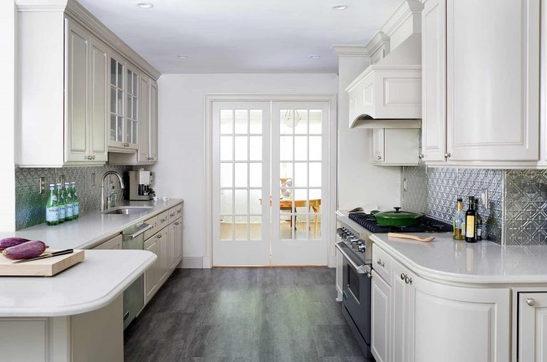 traditional kitchen with cream cabinetry and gray wood floors stainless steel backsplash and appliances crown molding french doors