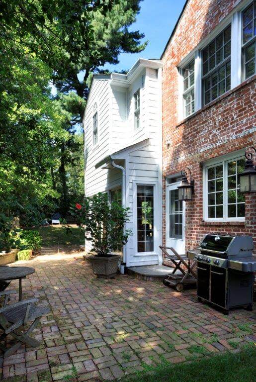 large addition on traditional style brick maryland home leads out to patio