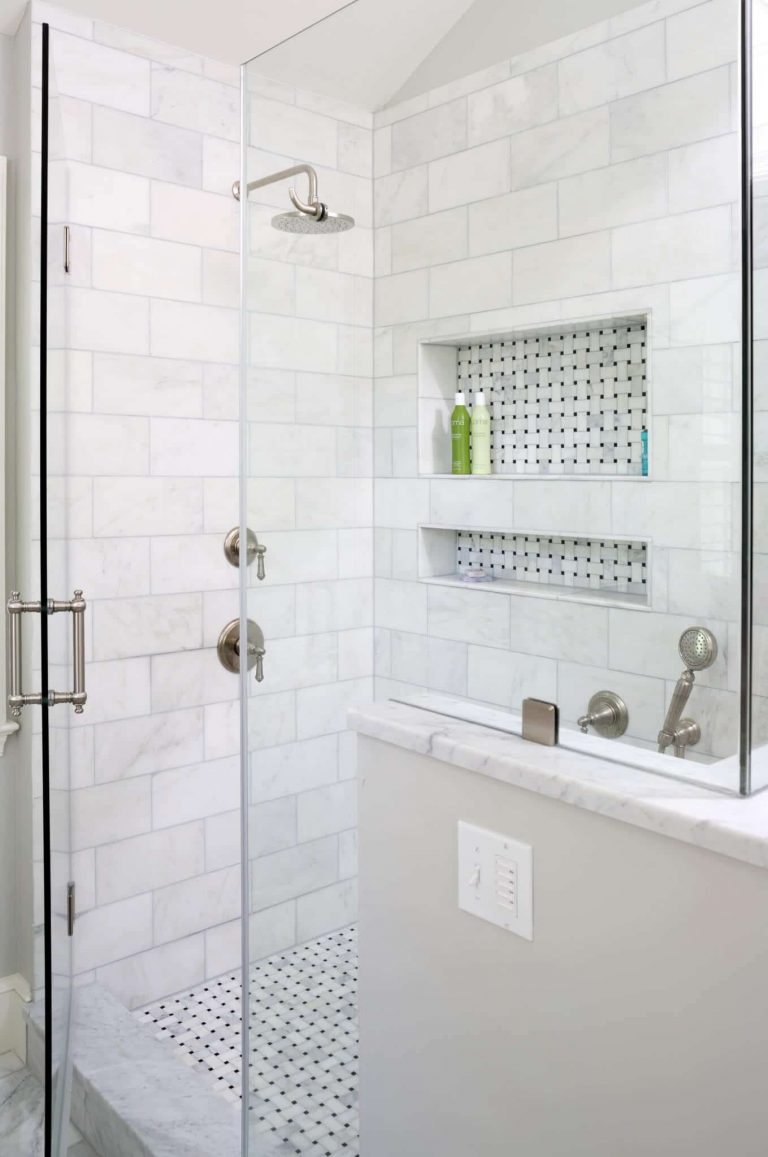 bright and large shower stall with glass doors and built in storage nook with accent tile and rain showerhead