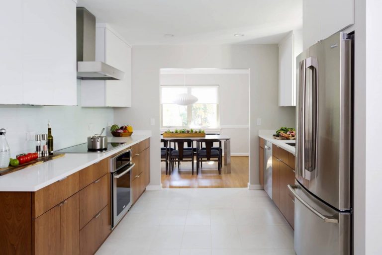 bright modern kitchen natural wood and white cabinetry stainless steel appliances leads to dining room
