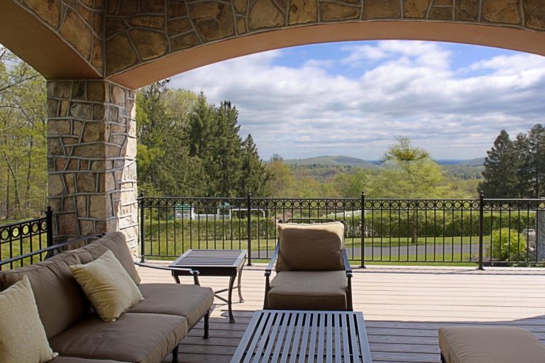 side porch addition with arched stone openings and iron railings