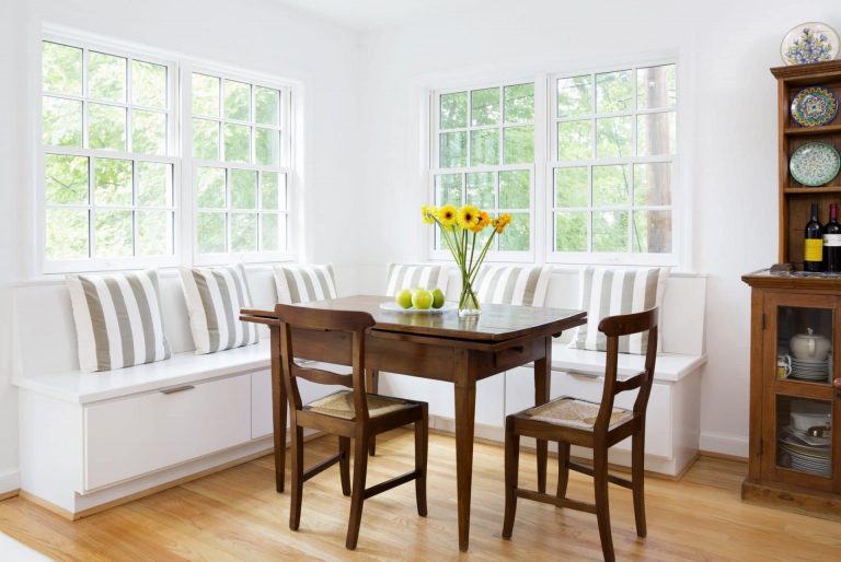 large windows in bright white eat in area banquette seating with storage underneath