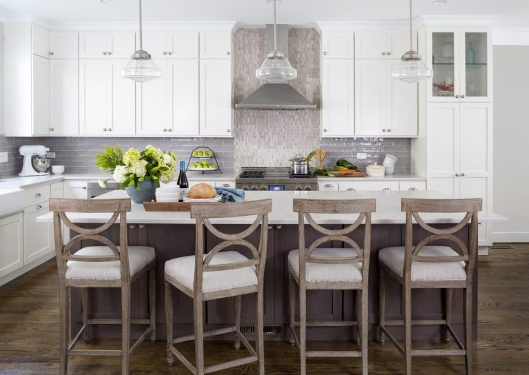 kitchen with neutral and gray color palette white upper cabinets center island with seating and pendant lighting above tile backsplash with feature tile to ceiling behind range hood