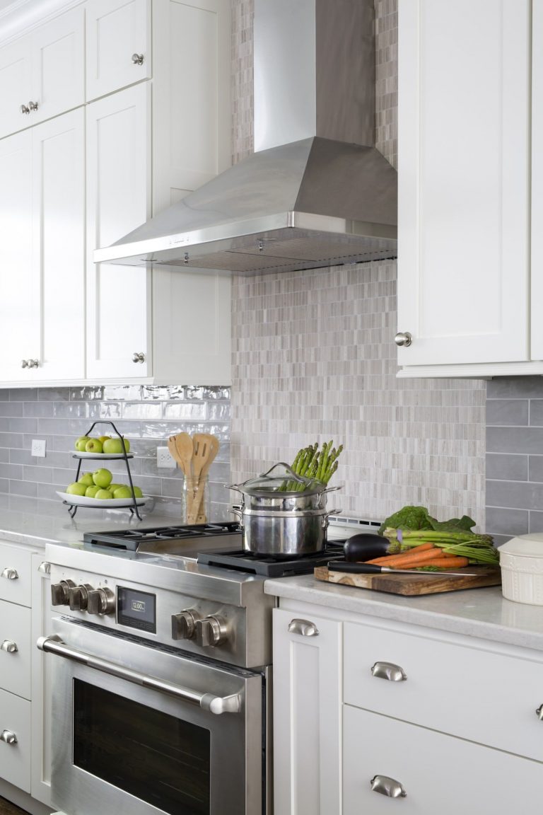stainless steel gas range and hood backsplash feature tile to ceiling