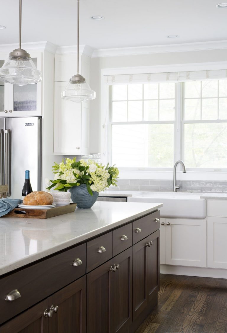 two toned cabinetry contrast porcelain apron sink pendant lighting over island large window over sink