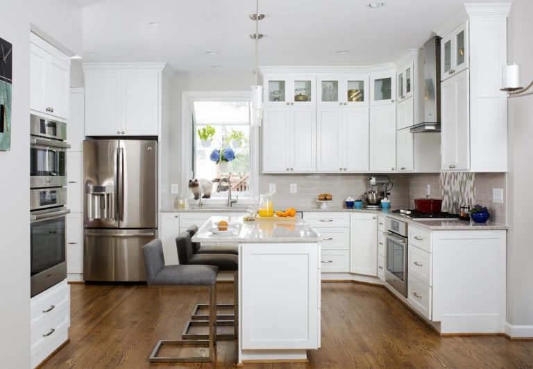white kitchen with wood floors center island with seating and pendant lighting above