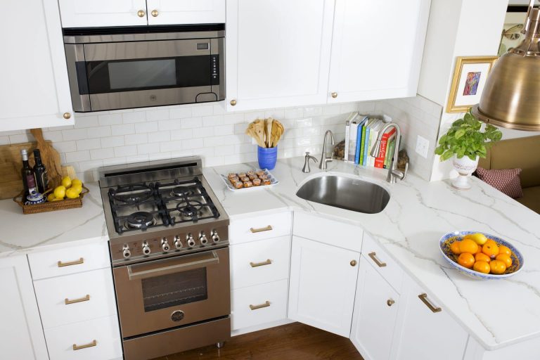 kitchen with white cabinetry and subway tile backsplash stainless steel appliances gold hardware and accents