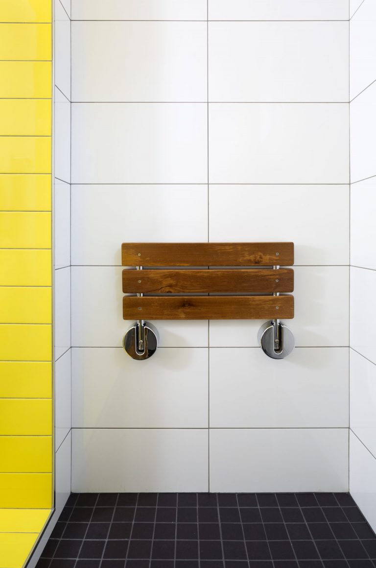 built in wooden shower bench and pop of color yellow tile