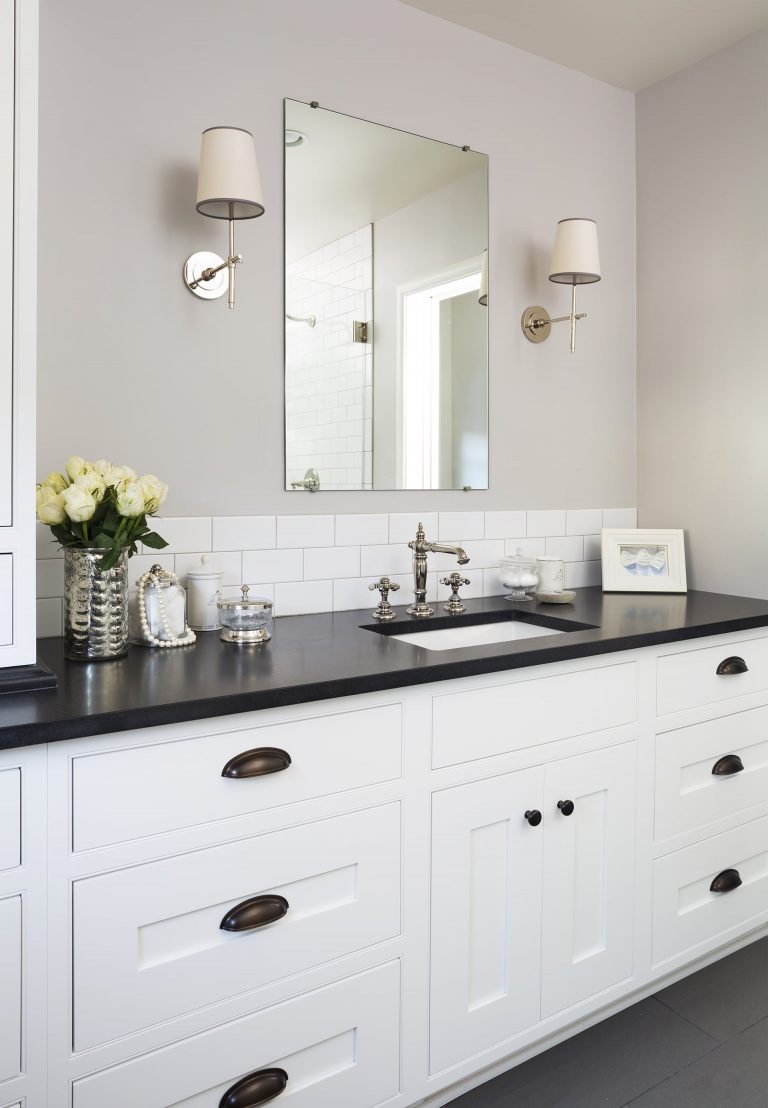 traditional bathroom white cabinets black floor and counter tops sconce lighting