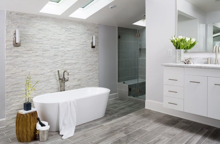 modern bathroom freestanding tub tile floors look like wood textured stone feature wall skylight gray color palette