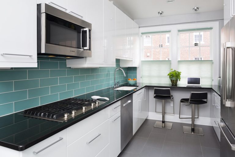 modern kitchen white cabinetry black countertops teal subway tile backsplash