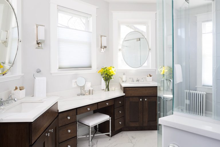 bright elegant bathroom with double sinks and built in vanity dark wood cabinetry