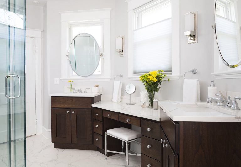 bright elegant bathroom with double sinks and built in vanity dark wood cabinetry