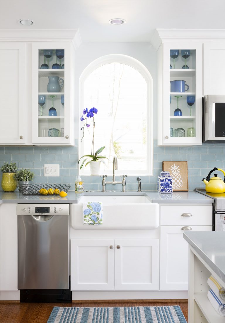 traditional kitchen light blue color palette white cabinetry with glass door uppers farmhouse sink arched window mini stainless steel dishwasher