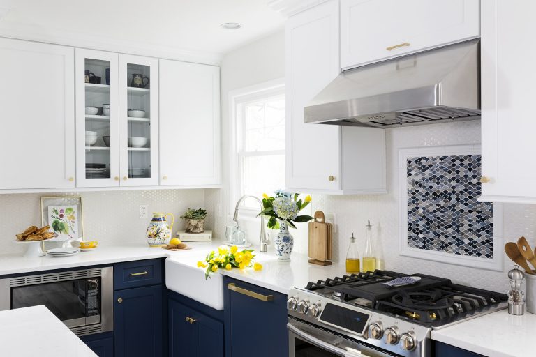 farmhouse porcelain sink glass door upper cabinetry stainless steel gas range and hood mosaic tile backsplash detail