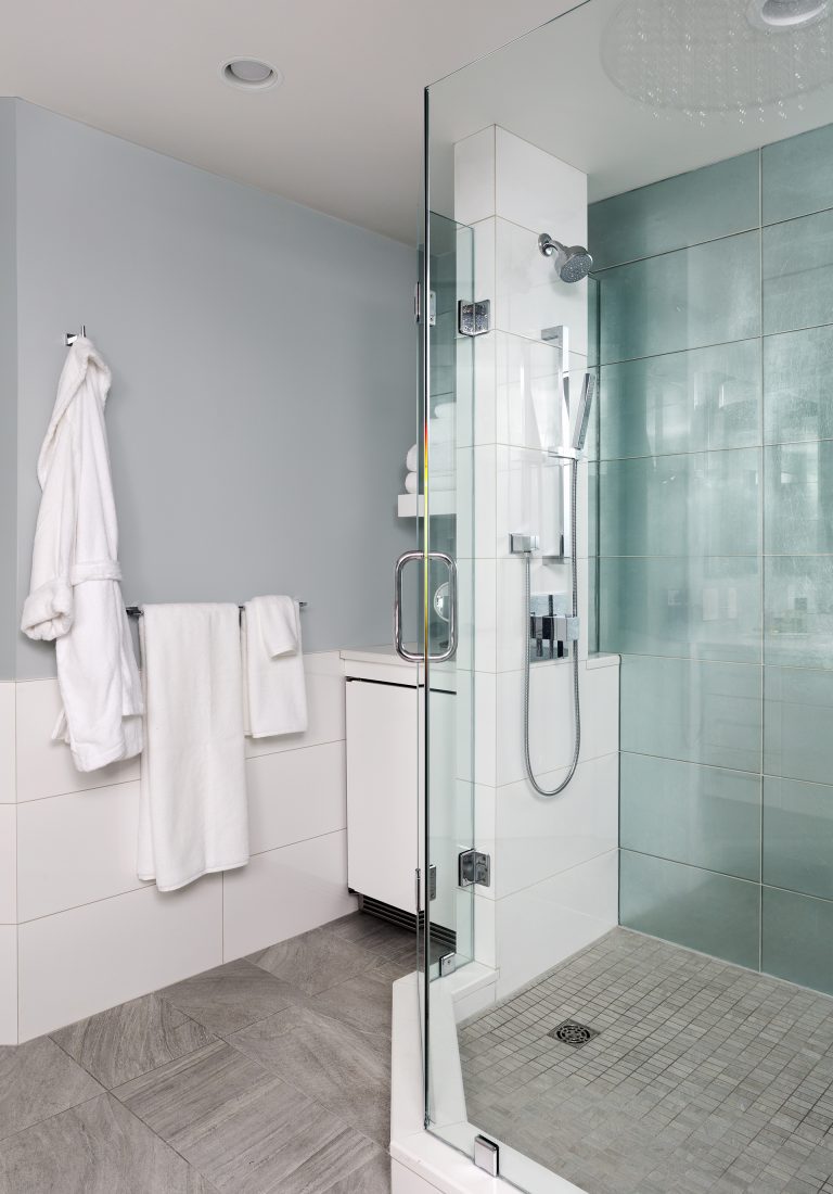 bathroom with soft blue color palette white cabinetry separate shower stall with glass door mirrored tiles