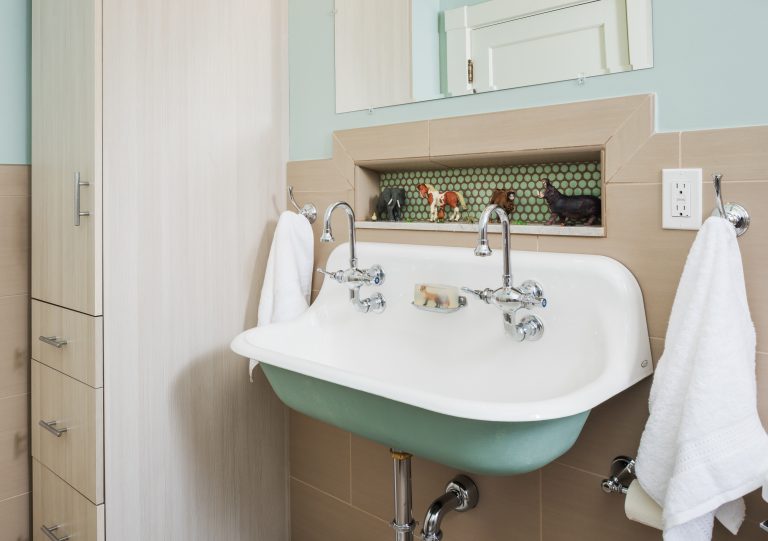 double sink with exposed pipes accent tile in storage nook and cabinet storage soft pink and teal colors