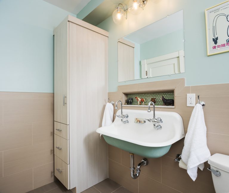 double sink with exposed pipes accent tile in storage nook and cabinet storage soft pink and teal colors