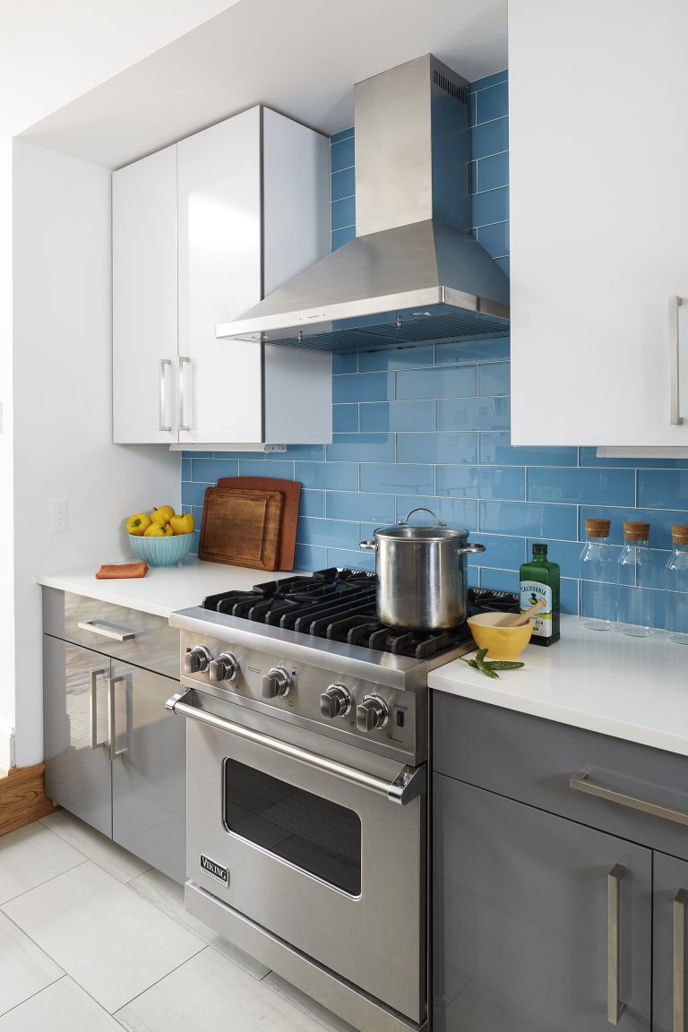 modern kitchen with gray and white cabinetry blue tile backsplash stainless steel appliances