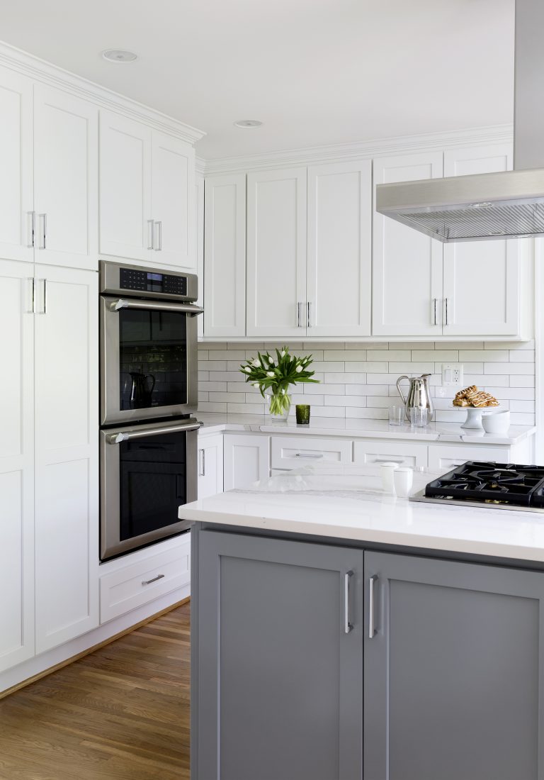 kitchen with white outer cabinetry and gray island cabinetry wall oven stainless steel appliances subway tile backsplash