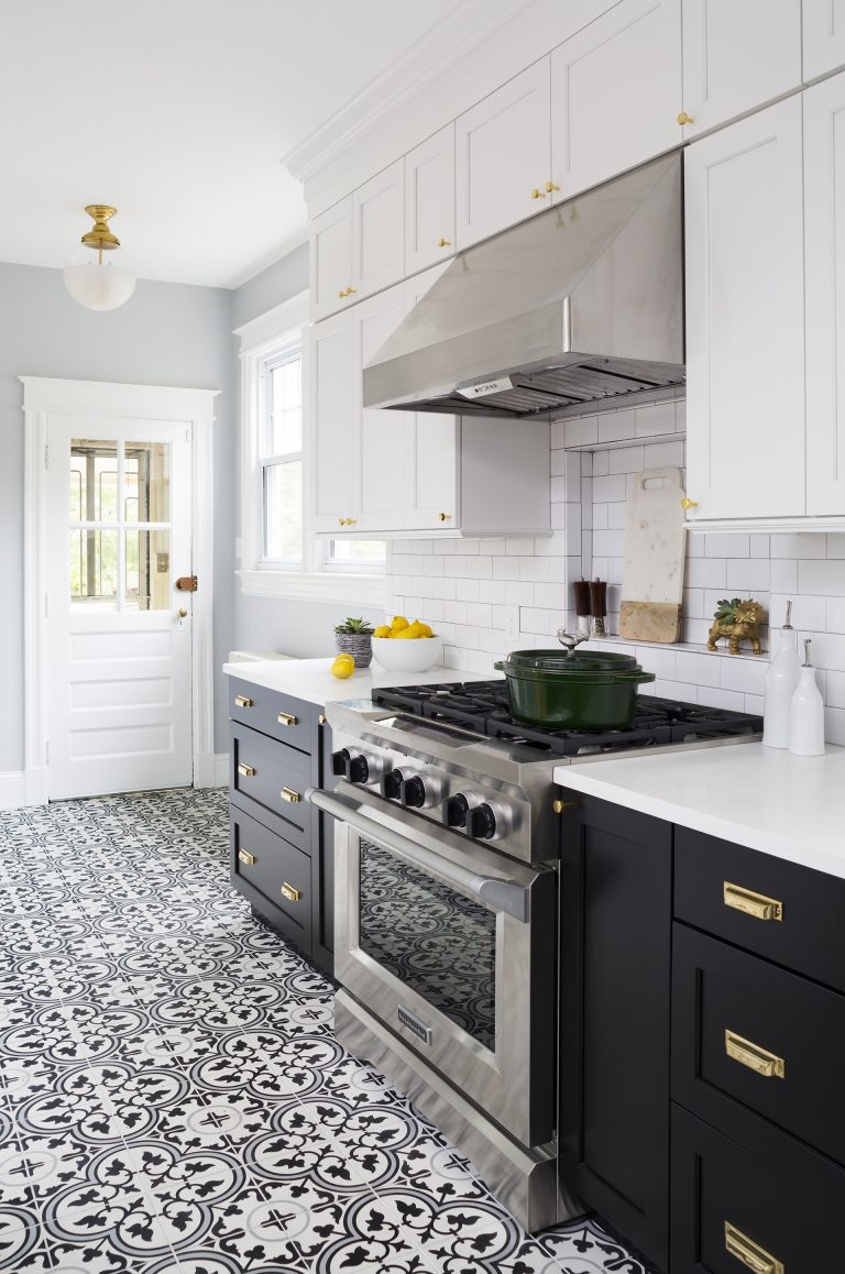 black and white kitchen with patterned tile floors gold accents and stainless steel appliances