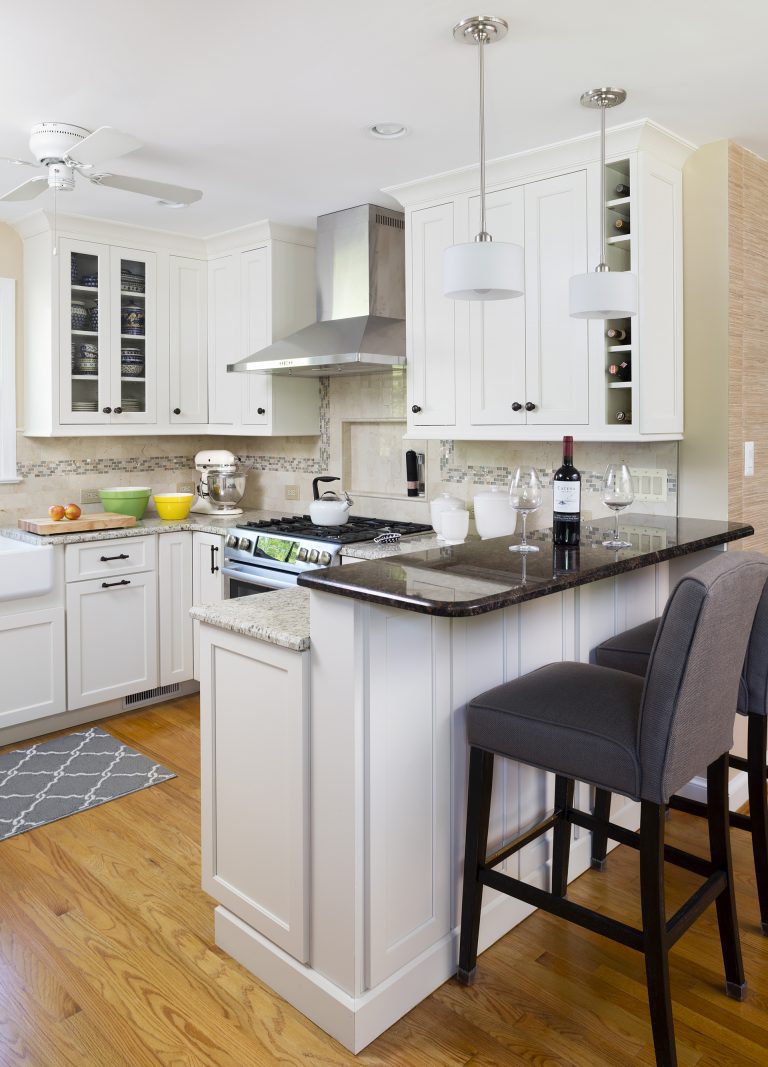 beige and white kitchen with wood floors peninsula with seating and pendant lighting above