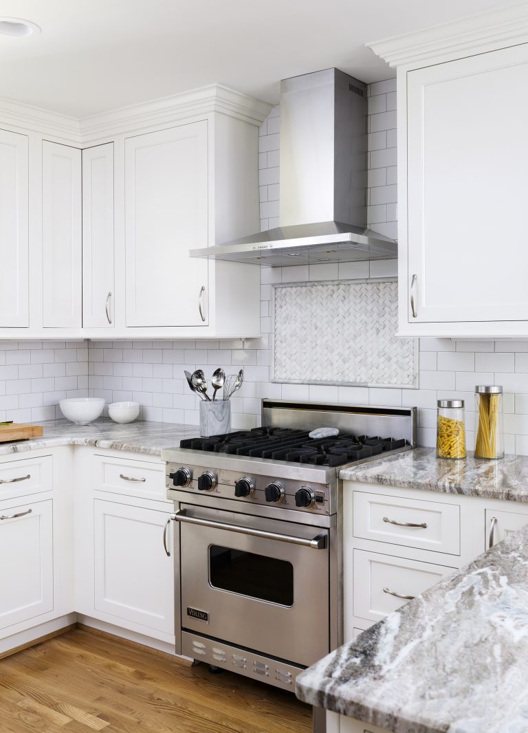 stainless steel gas range and hood mosaic tile backsplash detail