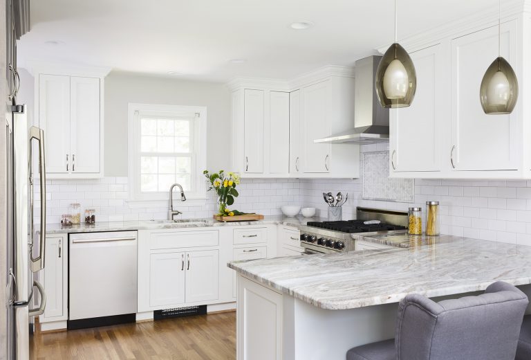 bright white kitchen with stainless steel appliances and peninsula with seating